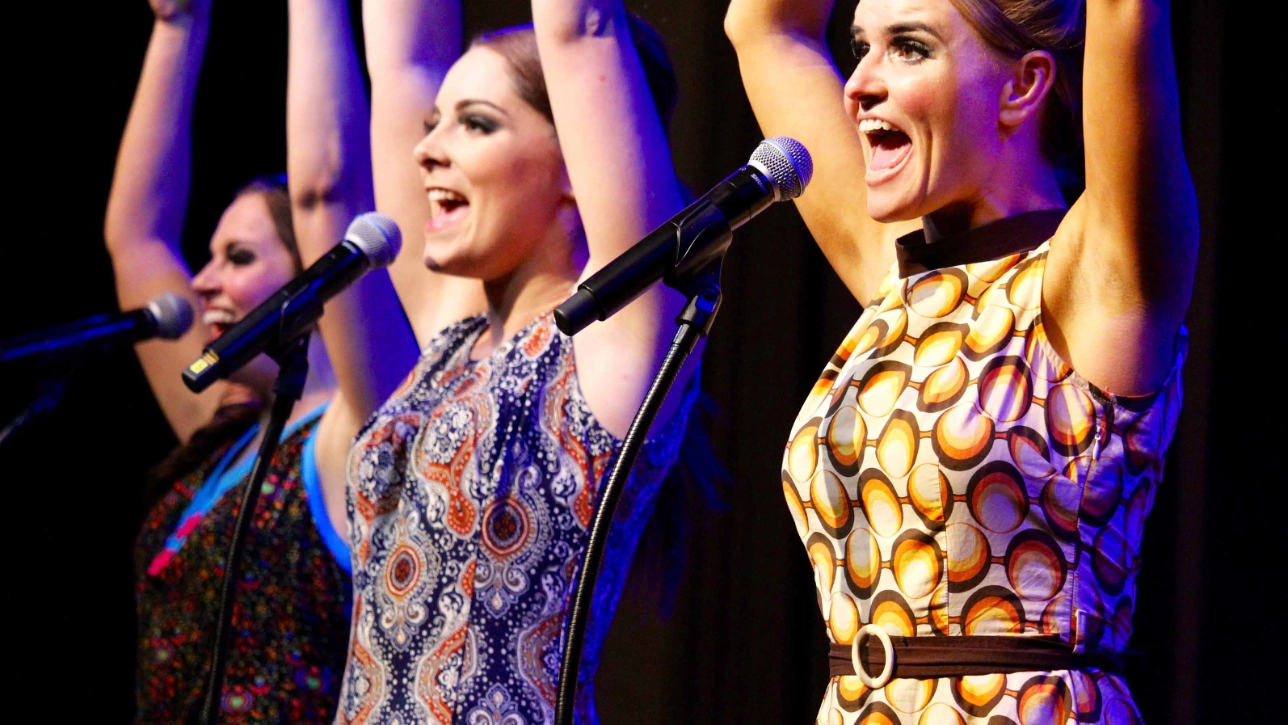 Three singers on stage with microphones 